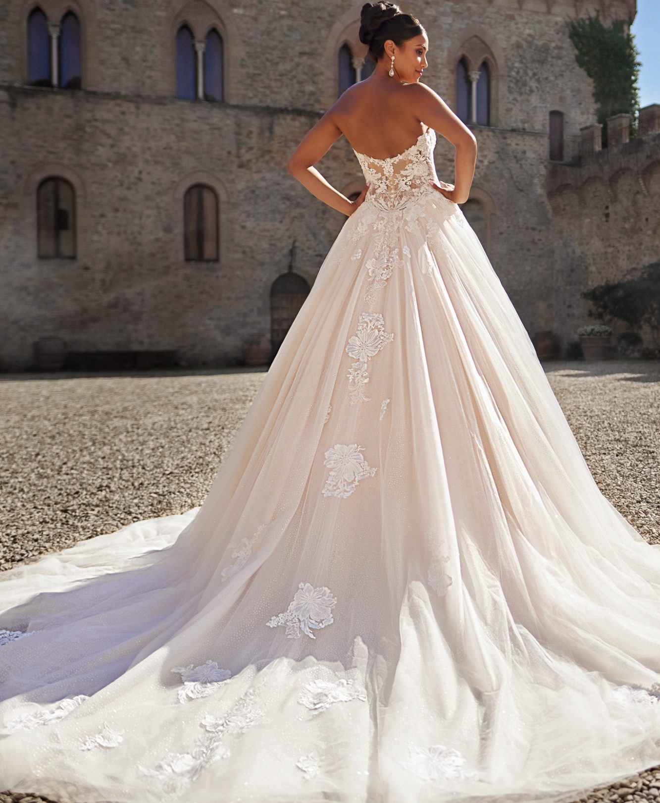 Braut in einem elegantem, schulterfreien Hochzeitkleid mit voluminösem Rock, vor einem historischen Gebäude. www.brautoutlet-warendorf.de