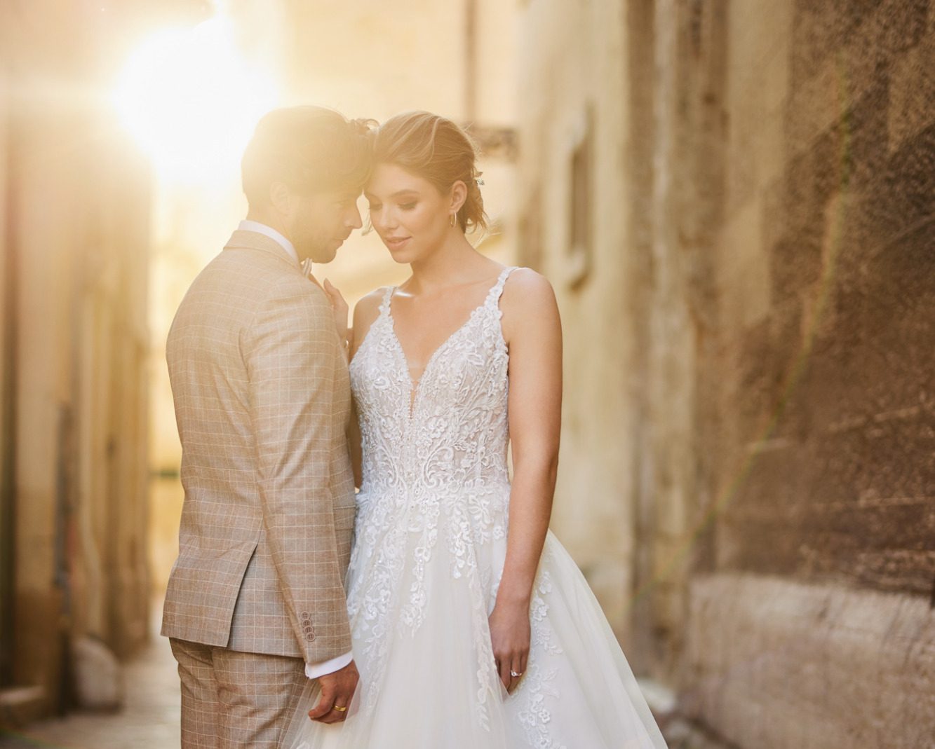 Braut und Bräutigam stehen sich in einer romantischen Gasse zugewandt gegenüber. BAO - Warendorf, www.brautoutlet-warendorf.de